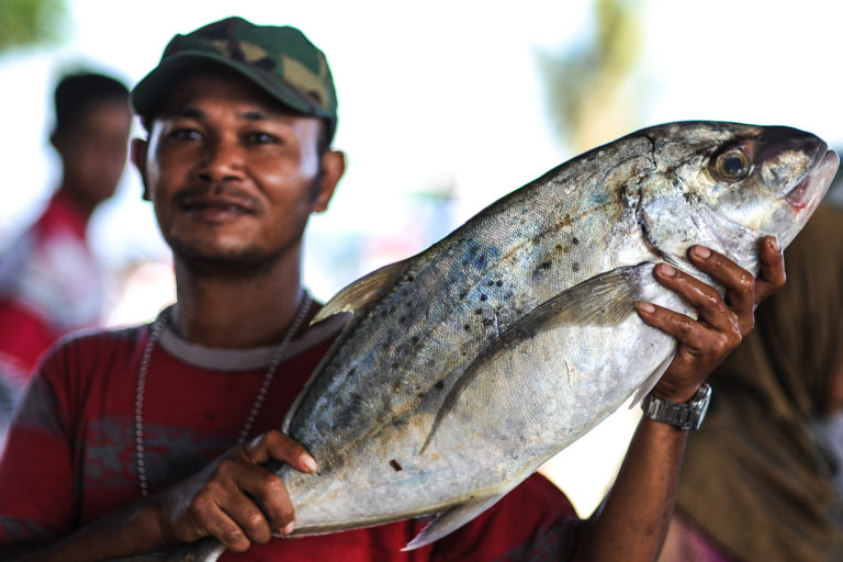 A fisherman shows off his catch at a market in Indonesia.