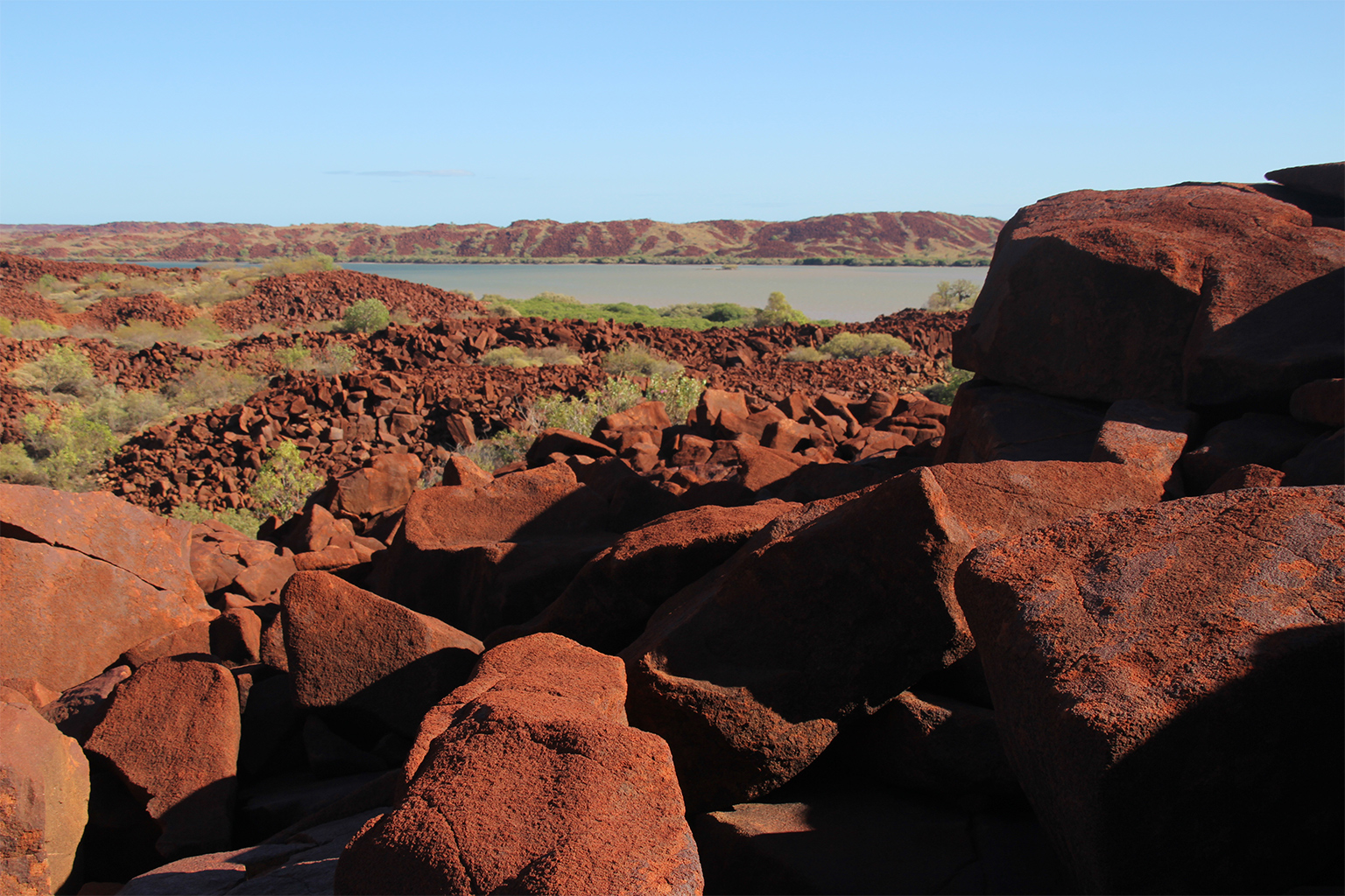 Formed billions of years ago from volcanic magma, the red rocks and hills of Murujuga arise in striking contrast to the surrounding green native grasses. 